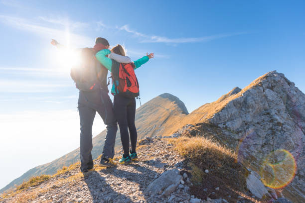 istock Hiker couple standing on a mountain ridge celebrating success 1671726113