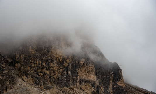 Cloudy fogy sky mountain peaks covered in mist in the morning. Dolomite rocky mountains Italy.