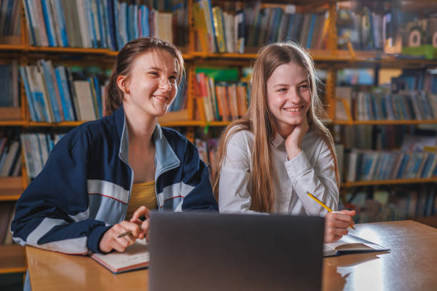 istock Two girls using a laptop during online lessons in the library 1671800818