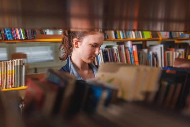 istock Girl student walking in the library searching for a book 1671804546