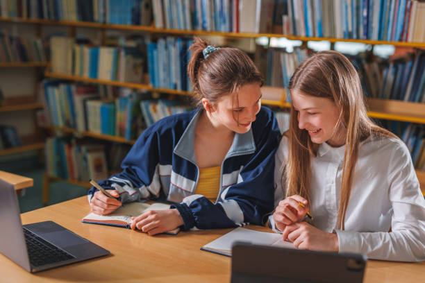 istock Two girls using a laptop during online lessons in the library 1671804563