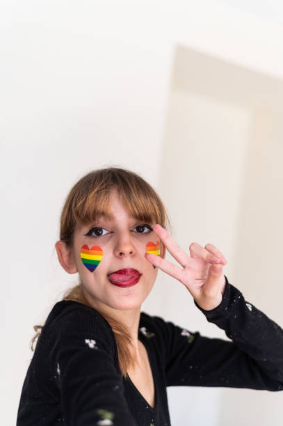 istock Girl with lgbt flag painted on face gesturing peace 1671836401