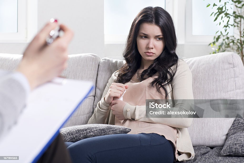 Psychiatrist and woman patient Oppressed young woman on reception at the psychologist Adult Stock Photo