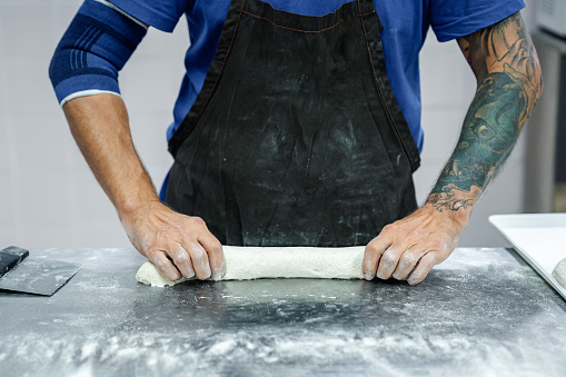 Close-up of baker making bread in his bakery. Small business concept