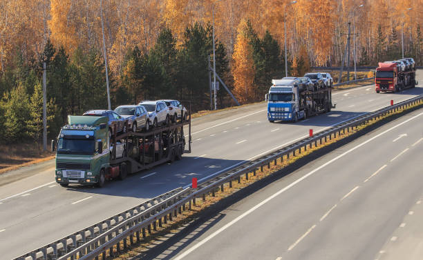 istock Car transporter trucks are moving along the highway 1671864836