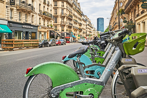 Paris, France - July 11, 2023: Rental bikes in the cityscape of Paris. In the background the tower of Montparnasse.