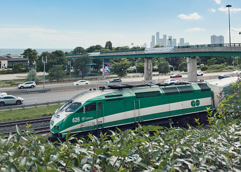 Toronto, Ontario. August 12th, 2023. A GO Train travels along the Gardiner Expressway with Lake Ontario in the background.