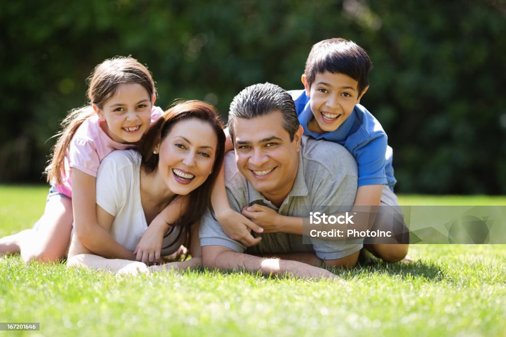 Crianças abraçando pais, deitados em Park - Foto de stock de 10-11 Anos royalty-free