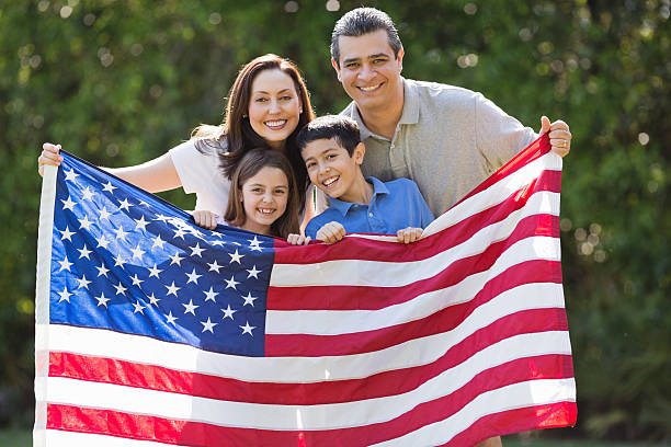 familia sonriendo mientras sostiene bandera estadounidense en el parque - fourth of july family flag american flag fotografías e imágenes de stock