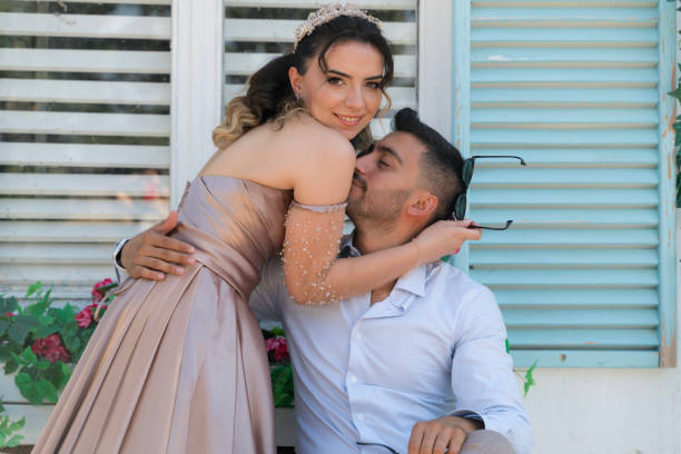 The young couple is celebrating their engagement. The man wore a suit and the young woman wore a long dress. very happy young couple posing for camera and having fun.