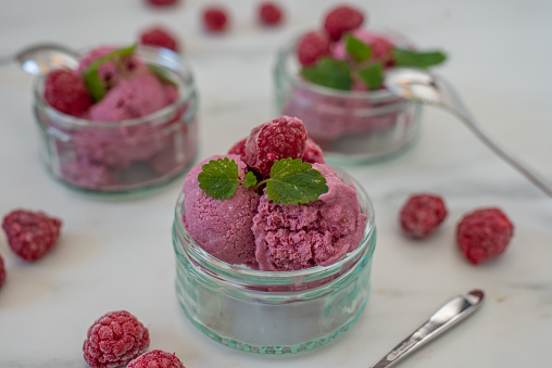 Tasty dessert for vegans, curd with berries garnish by mint leaf.