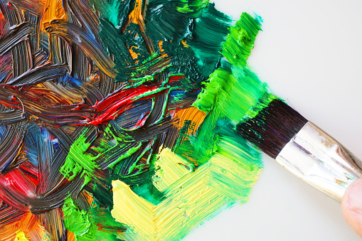 Young asian woman mixes paints on a palette in art studio