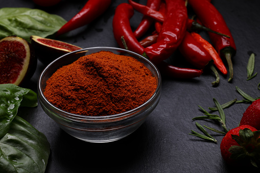 Red chilly powder in bowl with dried red chillies over white background