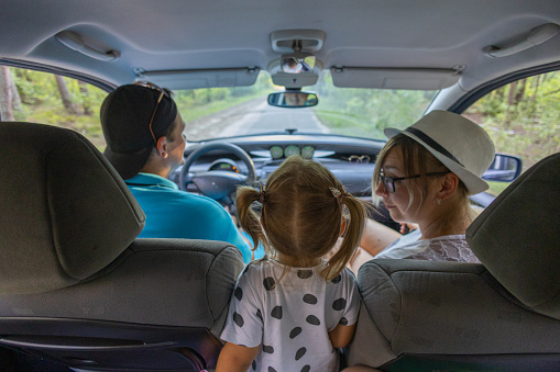 While traveling by car, the family stopped to rest. The child approached his parents in the car and talked to them. The family enjoy car travel and spend time happily together..