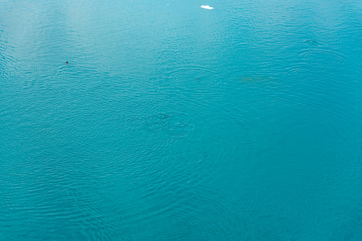 The surface of the sea, which has a shimmering blue-green color. The water looks calm and tranquil, with small waves creating ripples on the surface.