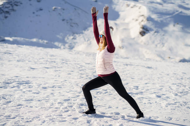 istock Slim woman stretching in warrior pose over snowy mountains 1672082079
