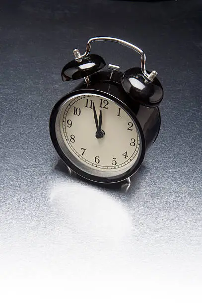 Vintage black alarm clock on metallic background