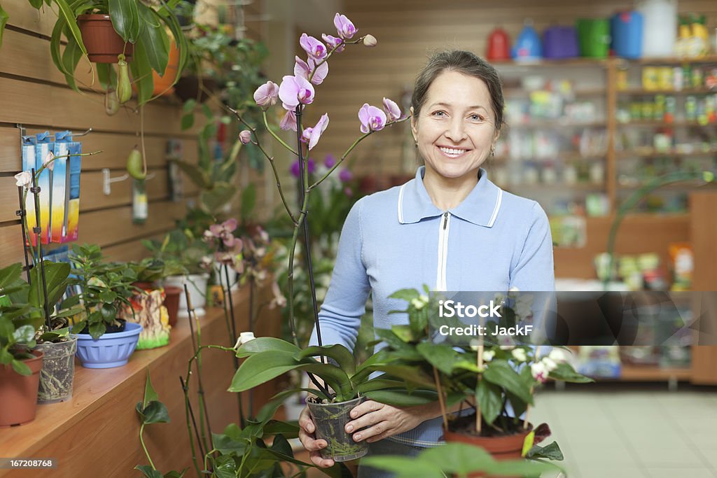 Donna con fiore orchidea in negozio - Foto stock royalty-free di Adulto