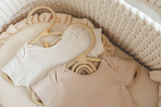 istock Two neutral bodysuits in a baby cradle, baby clothes 1672102049