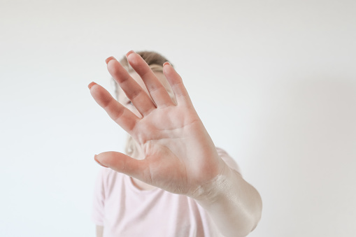 Don't shoot me! Dissatisfied blonde female in shirt showing stop sign with outstretched hand. Negative emotion, facial expression.