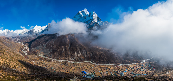 Ama Dablam’s jagged peaks soaring over the Sherpa farms in Dingboche overlooked by Lhotse, Island Peak and Baruntse high in the Himalayan mountains of Nepal.