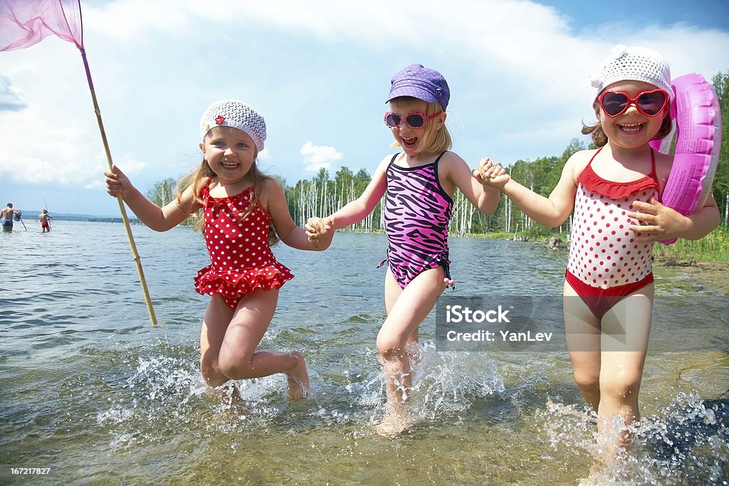 Children having fun on the beach Three little funny  cute girls running on coast together Active Lifestyle Stock Photo