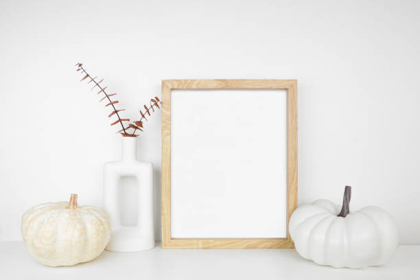 istock Mock up portrait wooden frame with fall braches and pumpkin decor on a white shelf 1672180774