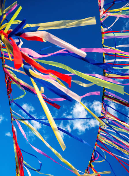 istock Multicolored ribbons or garlands flutter in the wind on a summer sunny day with a blue sky with clouds.The concept of a festive decoration for religious ceremonies. Retreat yoga festival 1672192177