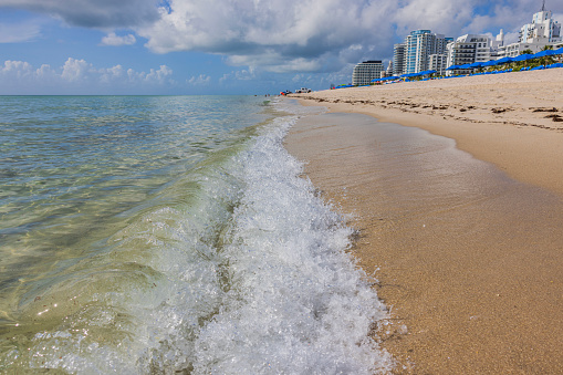 Beautiful view of wave rolling on to white sandy beach of Atlantic Ocean and blue sky with white clouds. Miami Beach. USA.