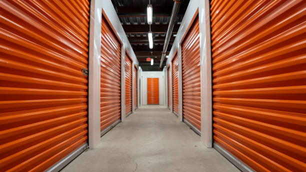 istock Empty hallway with orange  garage doors of a self storage unit warehouse. 1672207540