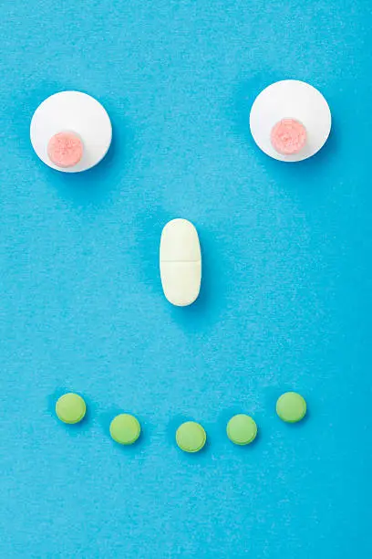 Happy smiley made of drugs on blue background.