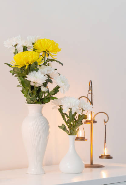 istock chrysanthemums flowers in vases and burning candles on white interior 1672234713