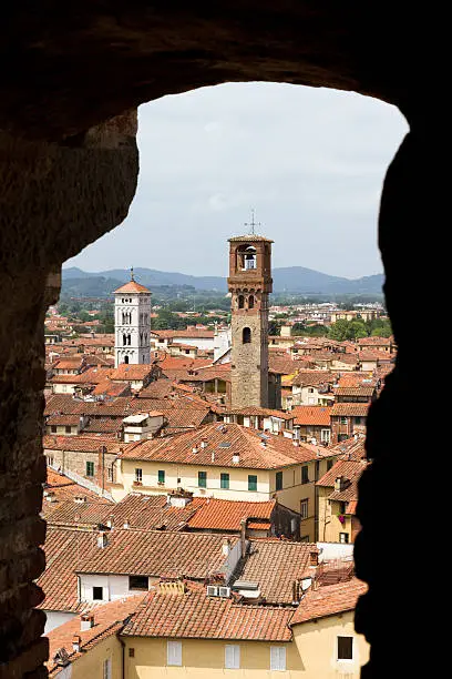 Look through a window onto two towers of the city of Lucca in Tuscany, Italy, from inside the the Guinigi tower
