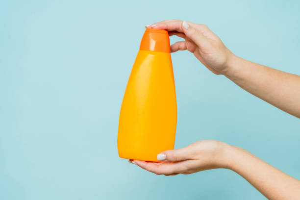 istock Woman's hand holding packaging of shampoo or conditioner on blue background. Copy space and mock up 1672254600