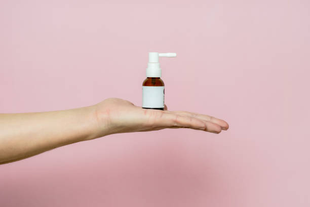 istock Hand holding a glass spray bottle with pink background 1672255151