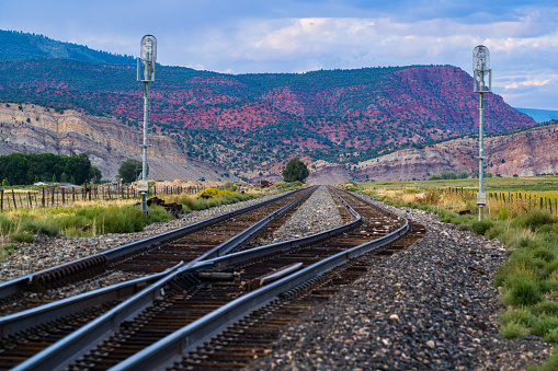 Railroad Tracks in Rural Scenic Area - Tracks leading off into distance with red rock canyons, mountains and agricultural valley.