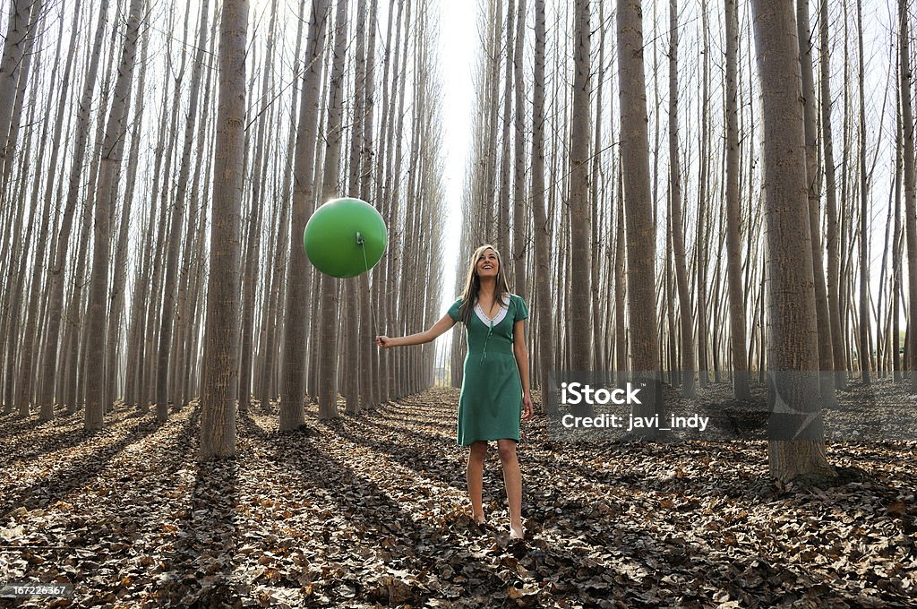 Beautiful blonde girl, dressed in green, walking into the forest Adult Stock Photo