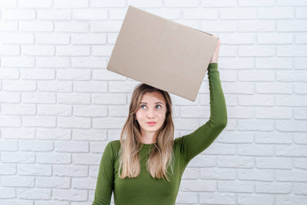 istock Attractive woman with parcel box on her head. Delivering a parcel 1672271511