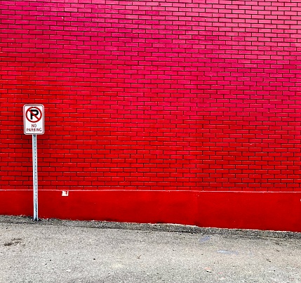 An isolated No Parking sign against a Christmas red brick wall.
