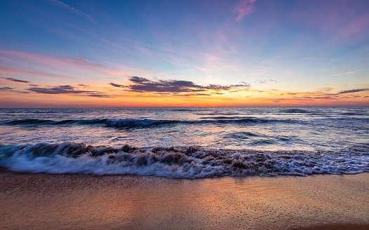 A tranquil beachscape featuring a golden sunset over the ocean