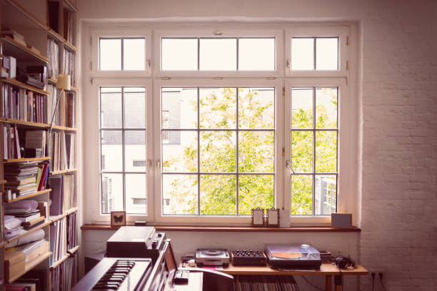 Window into the Music Room Large multi-panel casement window illuminating a lived-in music room. bay window stock pictures, royalty-free photos & images