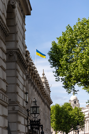 Whitehall government building in London with Ukrainian flag raised in solidarity with Ukraine on blue sky