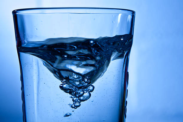 Vortex in a glass of water against a blue background
