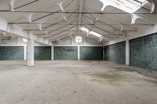 Empty white hall of an industrial building with walls crammed with formulas on a green chalkboard