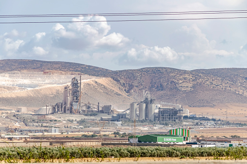 Oggaz, Mascara, Algeria- May 3, 2023: Recycling plant for polypropylene (PP) plastic and high-density polyethylene (HDPE) plastics. Trees, mountains and blue cloudy sky.