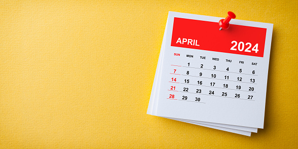 Nota adhesiva blanca con calendario de abril 2024 y pin rojo sobre fondo amarillo photo