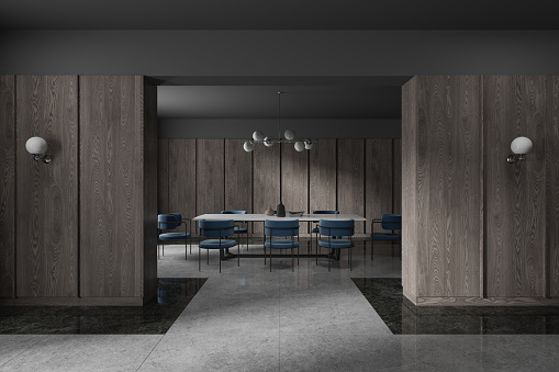Interior of stylish luxury dining room with gray and dark wooden walls, marble floor and long dining table with blue chairs standing near it. 3d rendering