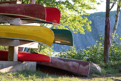 Bon Echo Provincial Park, Ontario - 2023-07-30 - Canoes stored neatly on a rack with Mazinaw Rock looming in the background.