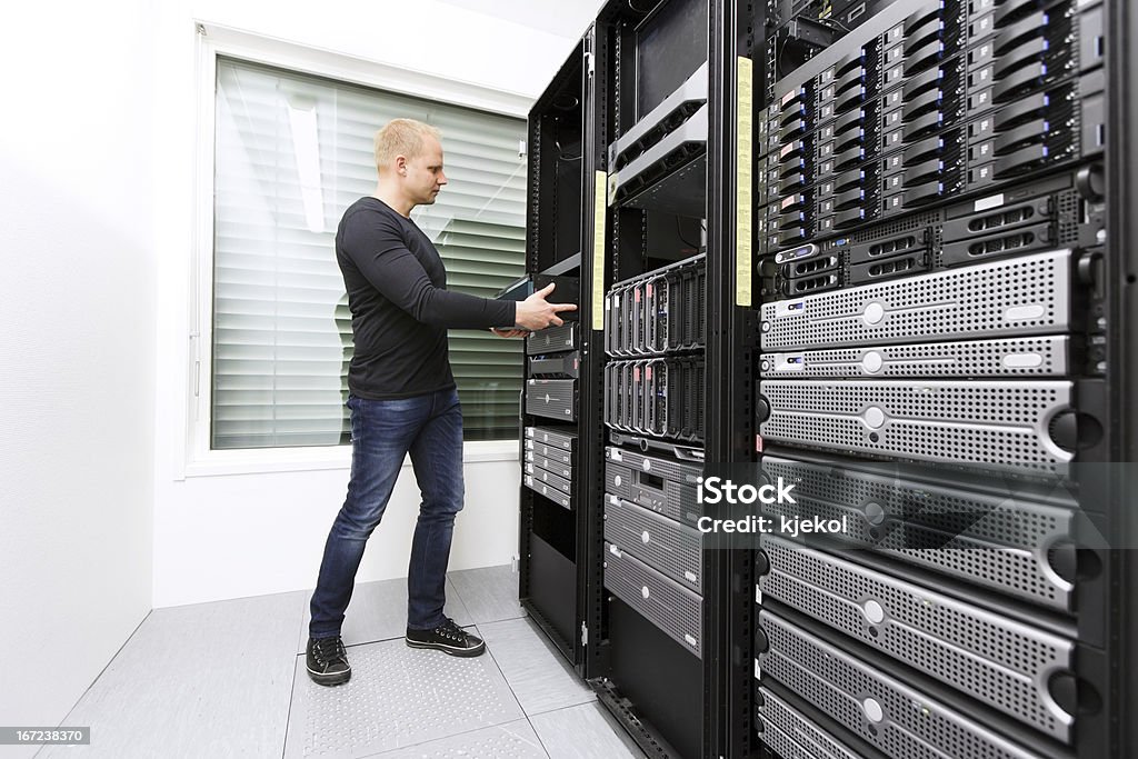 Install Network Router in Datacenter It engineer / consultant wokring and install / inserts  a router / switch in a data rack. Shot in a data center. 25-29 Years Stock Photo