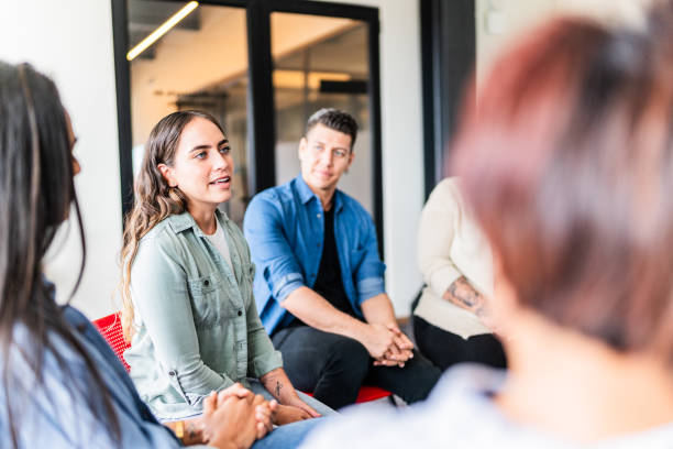 mid adult woman introducing herself in group therapy at mental health center - groepstherapie stockfoto's en -beelden